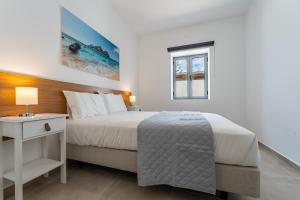 a white bedroom with a bed and a window at Casa Turalves - By WeHostMadeira in Porto Santo