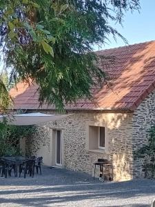 a stone building with tables and chairs in front of it at Gîte cosy 6 personnes, avec jardin en Normandie, proche des plages du débarquement et du Mont Saint-Michel in La Luzerne