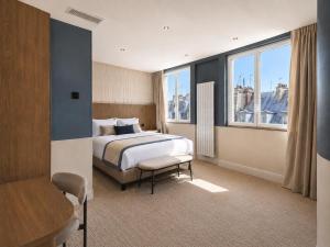 a bedroom with a bed and a chair and windows at 336 Saint-Honore By Chapitre Collection in Paris