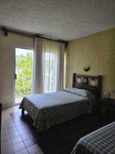 a bedroom with two beds and a large window at Hotel Plaza Palenque in Palenque +31 photos