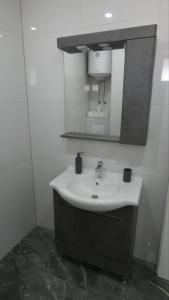 a white bathroom with a sink and a mirror at Sokak Apartman in Bihać