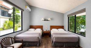 two beds in a room with two windows at Sina Suites Cancun - Adults Only in Cancún +32 photos