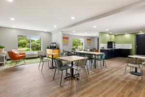 a cafeteria with tables and chairs and a kitchen at Spark By Hilton Freeport in Freeport