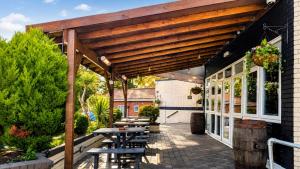 a wooden pergola with tables and benches on a patio at The Park Hotel - Sure Hotel Collection by Best Western in Diss