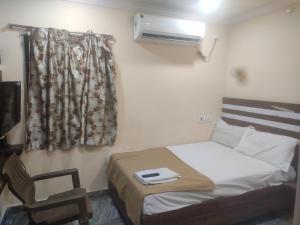 a small bedroom with a bed and a chair at HoTEL LAALASA in Vijayawāda +12 photos