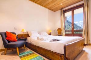 a bedroom with a bed and a chair and a window at Chalet Dava La Via ski in - ski out - Happy Rentals in Chamonix