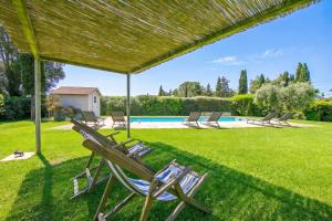 a group of lawn chairs under a pergola next to a pool at Chalet Vignarola - Happy Rentals in Orbetello