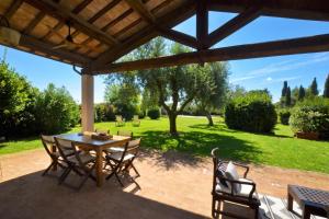 a patio with a table and chairs under a roof at Chalet Vignarola - Happy Rentals in Orbetello