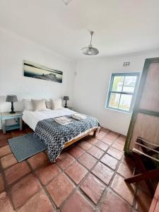 a white room with a bed and a window at Coast Cottages Langebaan in Langebaan
