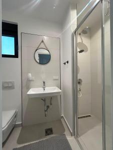 a white bathroom with a sink and a shower at L 32 Sea view in Lepetani