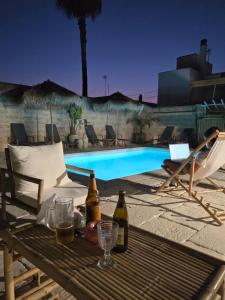 a table with bottles of beer sitting next to a swimming pool at LA PIGNA BLU CasaVacanza con Piscina in Botrugno