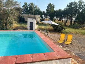 two chairs and an umbrella next to a swimming pool at Monte do Vale in Casa Branca