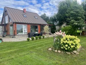 a house with a yard with flowers in front of it at Upes lillijas in Jelgava