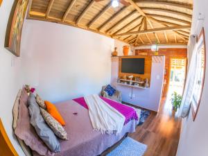 a bedroom with a bed and a flat screen tv at Chalé Flor de Ypê in Carrancas