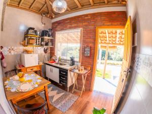 a kitchen with a table and a sink and a brick wall at Chalé Flor de Ypê in Carrancas