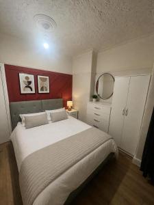 a bedroom with a large bed and a red wall at Northenden Stopsss in Manchester