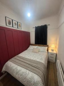 a bedroom with a large bed with a red headboard at Northenden Stopsss in Manchester