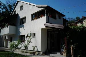 a white building with a balcony with flowers on it at Raiul Sânzienelor in Sărata-Monteoru