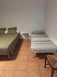 two beds in a room with a tiled floor at F1 plain-pied in Montjaux +3 photos