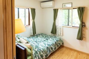 a small bedroom with a bed and two windows at 今帰仁森風テラス in Nakijin