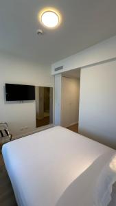 a bedroom with a white bed and a flat screen tv at Hotel João Paulo II in Braga