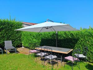 a table and chairs with an umbrella in the grass at Loft Pietrasanta in Pietrasanta