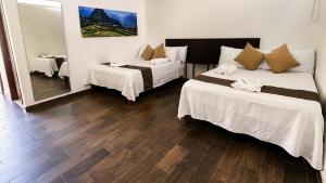 a hotel room with two beds and a mirror at Hotel y Jardín Las Asadas, Bar y Grill in Xochitepec