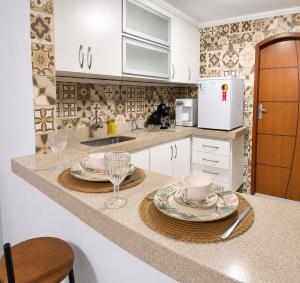 a kitchen with a counter top with two plates and glasses at G2 Hospedagem Suites & Studio Praia Dos Anjos in Arraial do Cabo