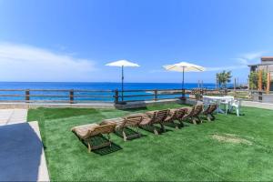 a row of chairs and umbrellas on a lawn with the ocean at CBreeze Guesthouse in Batroûn