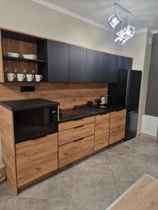 a large kitchen with wooden cabinets and a microwave at Lubanska by Tauron Arena in Zgorzelec +7 photos