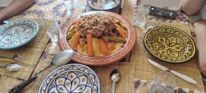 a table with a bowl of food and plates on it at Dar Rime in Ghazoua +3 photos