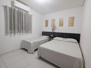 two beds in a room with white walls at Casinha Rústica in Indaiatuba