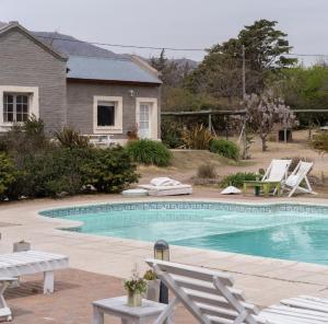 a swimming pool with white chairs and a house at DOS AGUAS in Capilla del Monte