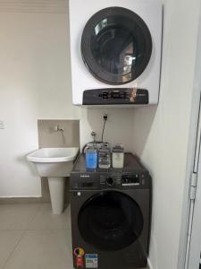 a microwave above a washing machine in a bathroom at Casinha Rústica in Indaiatuba +46 photos
