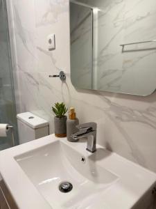 a white bathroom with a sink and a mirror at Refúgio d’Aldeia da Serra in Seia +30 photos