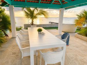 a white table and chairs on a patio with the beach at The Beach House Bonaire in Kralendijk