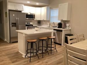 a kitchen with white cabinets and bar stools at Pickwick Dreams in Counce