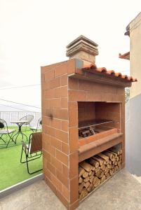 an outdoor brick oven with a pile of logs at Sea View Pedra Mar in Campanário