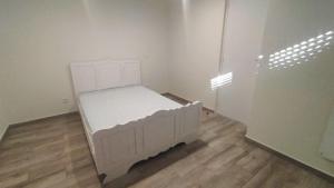 a white bed in a room with a wooden floor at AL - Bino - T3 in Carregosa