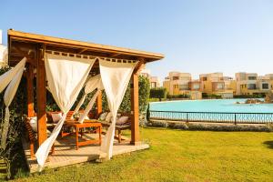 a gazebo with a table and chairs next to a pool at Luxury Marassi Villa on Lagoon in El Alamein