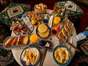 a table topped with plates of breakfast foods and orange juice at Riad Dar ElBellar in Fez