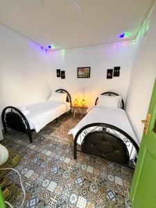 two beds in a room with a fireplace at Marrakech Premium Dar Aicha in El Gouassem