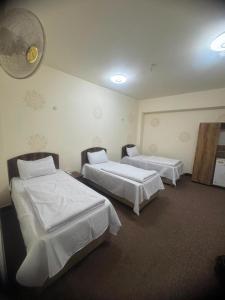 a room with two beds and a fan on the wall at فندق ومطعم درة علي in Qaryatal Karkāshīyah
