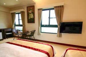 a bedroom with a bed and a tv and a table at Penghu Luna Sea Homestay in Magong