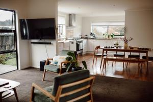 a living room with a table and a kitchen at Aurum Retreat in Reefton