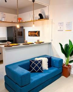 a blue couch in a room with a kitchen at Apartamento Centro Bertioga Casal e Família - Ar Condicionado - Praia da Enseada in Bertioga +20 photos