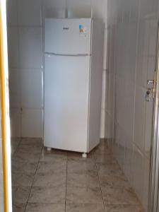 a white refrigerator in a kitchen with a floor at Casa Progresso in Juiz de Fora
