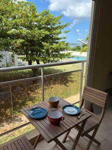 a wooden table with plates and bowls on a balcony at Studio Marigot Fort Louis in Marigot