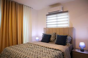 a bedroom with a bed with blue pillows and a window at Your Private Patio Oasis Spa Pool Lounge 2BR in Santiago de los Caballeros +24 photos