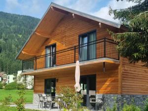 a log house with a balcony and tables and chairs at am Afritzer See in Afritz